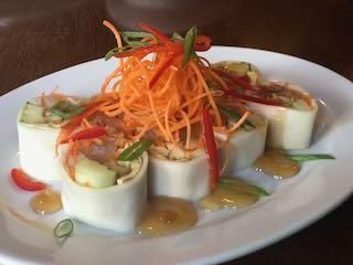 Fresh spring rolls sliced and topped with shredded carrot and sauce