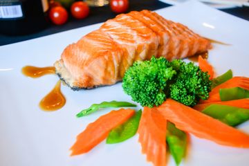 Salmon fillet with broccoli, carrots and sauce on a white plate