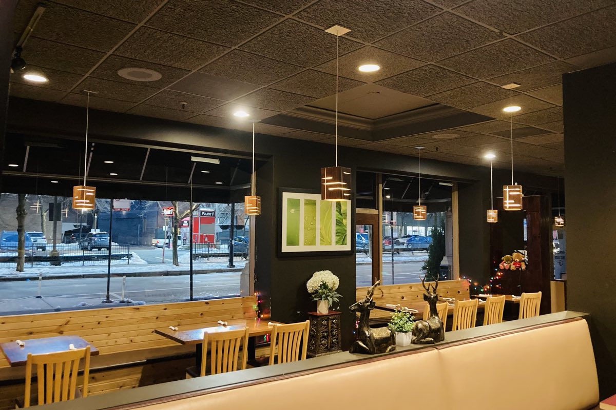 Window seating at Amarit with wooden benches, pendant lights and a view of Dearborn Street